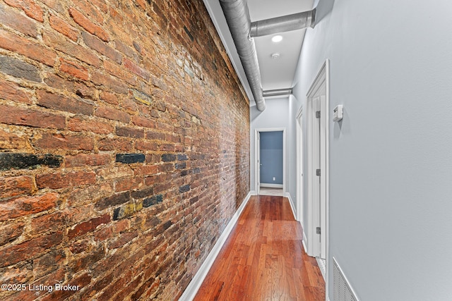 corridor featuring hardwood / wood-style floors and brick wall