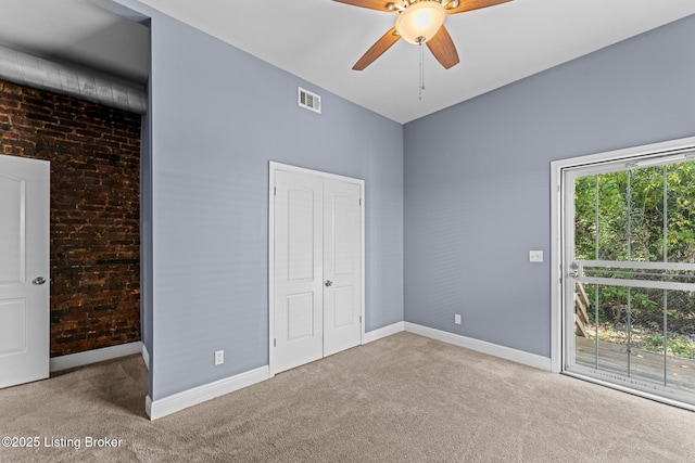 unfurnished bedroom with ceiling fan, carpet floors, and brick wall