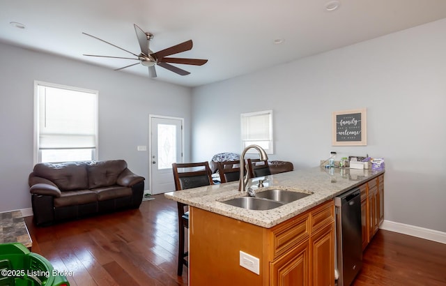 kitchen featuring dishwasher, ceiling fan, dark wood-type flooring, light stone counters, and sink