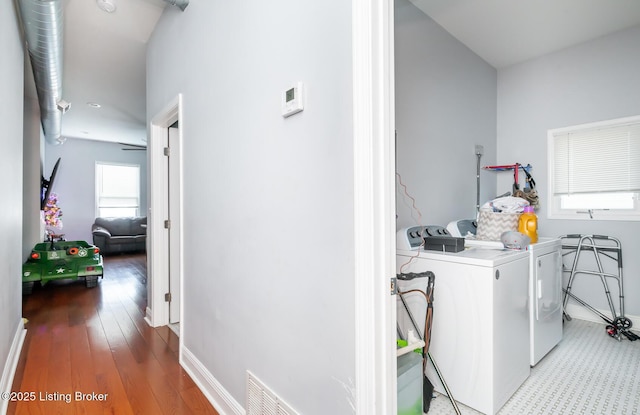 clothes washing area with washer and dryer, ceiling fan, and wood-type flooring