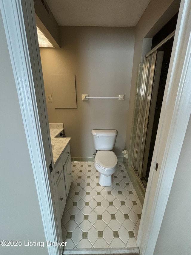 bathroom featuring toilet, a shower with shower door, and vanity