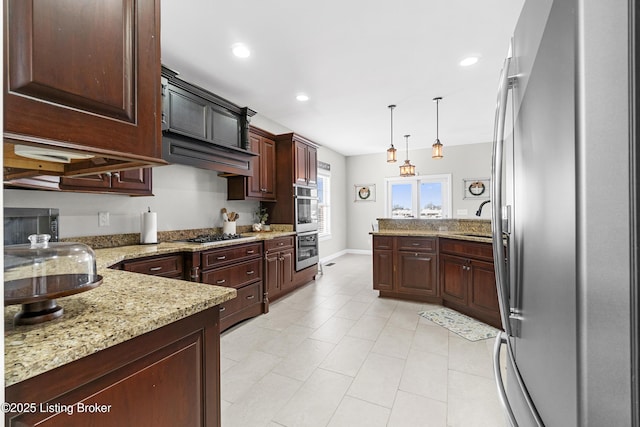 kitchen featuring appliances with stainless steel finishes, dark brown cabinets, light stone countertops, pendant lighting, and sink