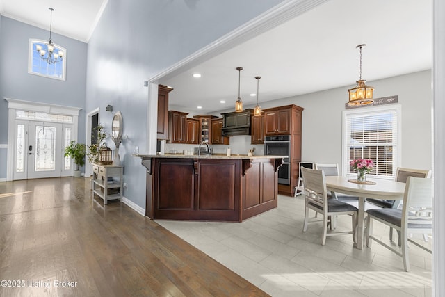 kitchen with a notable chandelier, hanging light fixtures, a breakfast bar area, stainless steel double oven, and light stone counters