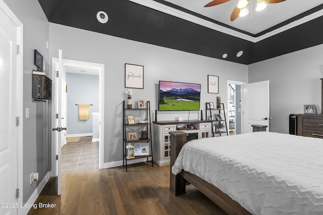 bedroom featuring ceiling fan, dark hardwood / wood-style floors, a tray ceiling, and ornamental molding