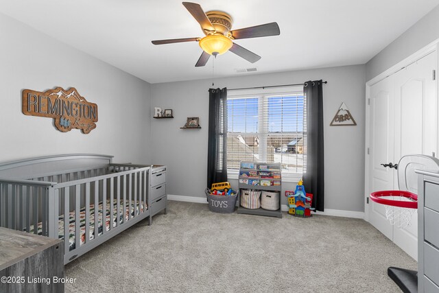 carpeted bedroom featuring ceiling fan and a crib