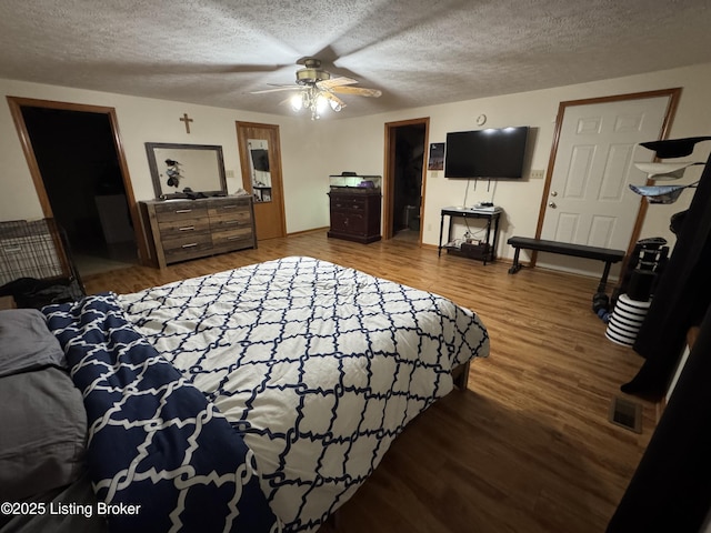 bedroom featuring ceiling fan, a spacious closet, a textured ceiling, and hardwood / wood-style floors