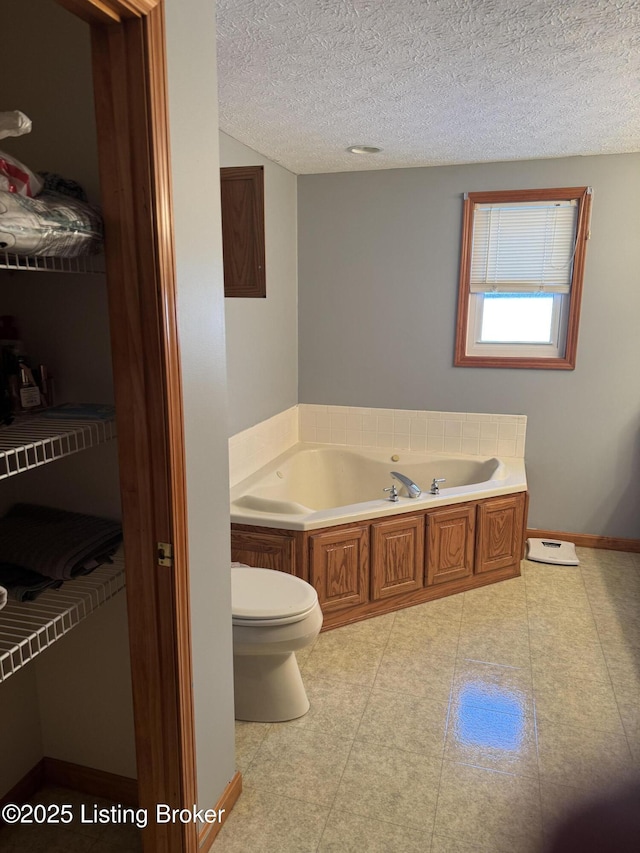 bathroom featuring a textured ceiling, toilet, and a tub to relax in