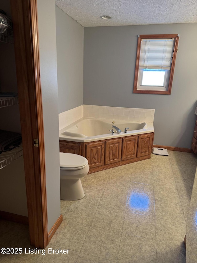 bathroom featuring a bathtub, a textured ceiling, and toilet