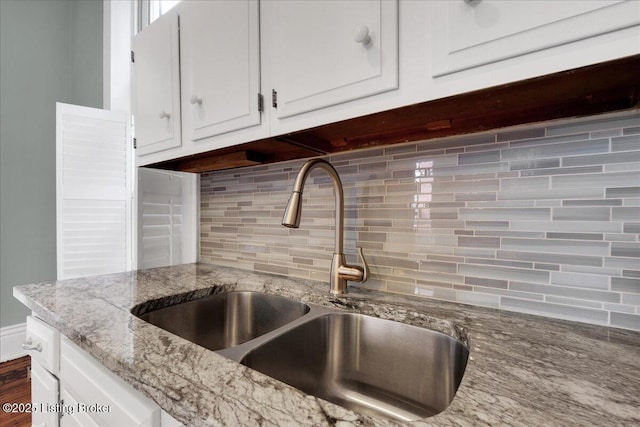 kitchen with tasteful backsplash, sink, light stone counters, and white cabinets