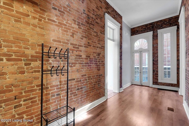 interior space with hardwood / wood-style floors, ornamental molding, french doors, and brick wall