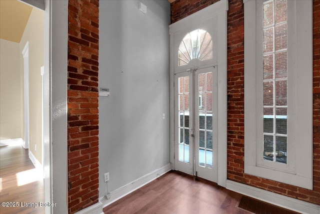 doorway featuring dark wood-type flooring and brick wall