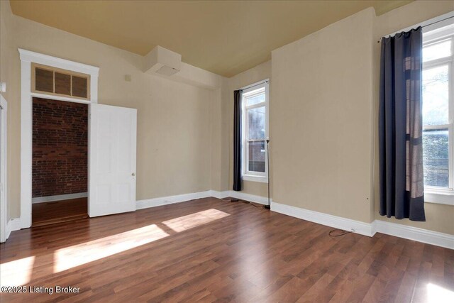 spare room with lofted ceiling, plenty of natural light, and dark hardwood / wood-style floors