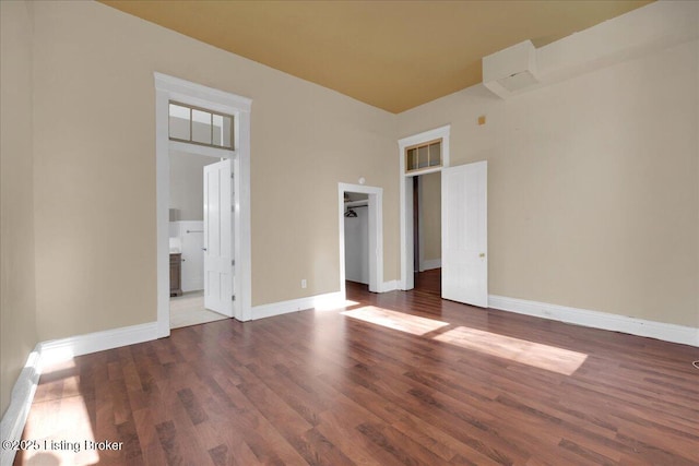 unfurnished bedroom featuring dark hardwood / wood-style flooring, connected bathroom, and a walk in closet