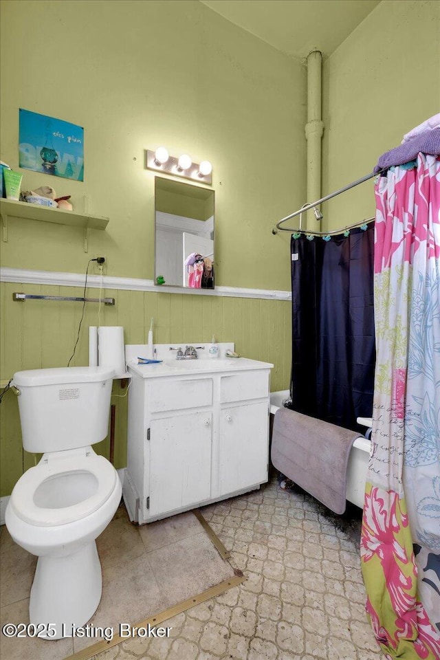 bathroom with vanity, toilet, and wood walls