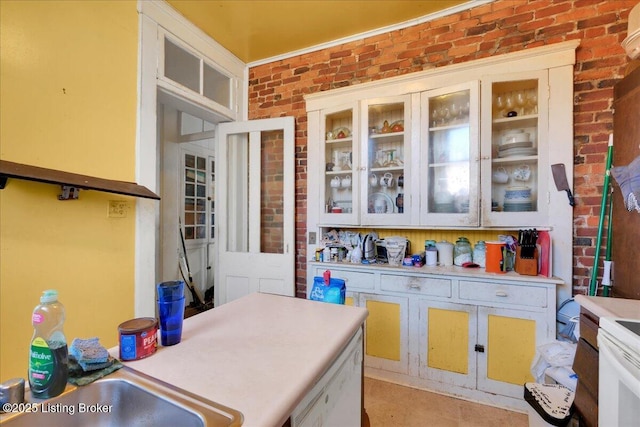 kitchen featuring white cabinetry, sink, white appliances, and brick wall