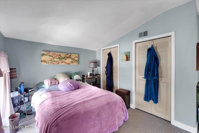 carpeted bedroom featuring multiple closets and vaulted ceiling