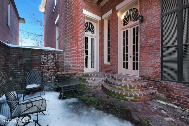 snow covered property entrance featuring french doors