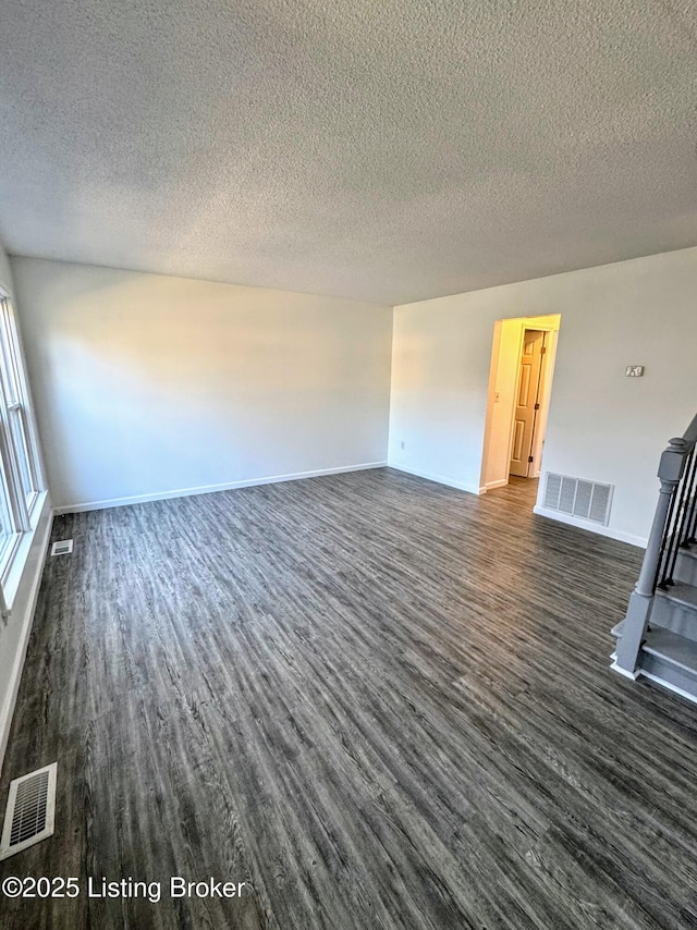 unfurnished living room featuring dark wood-type flooring and a textured ceiling