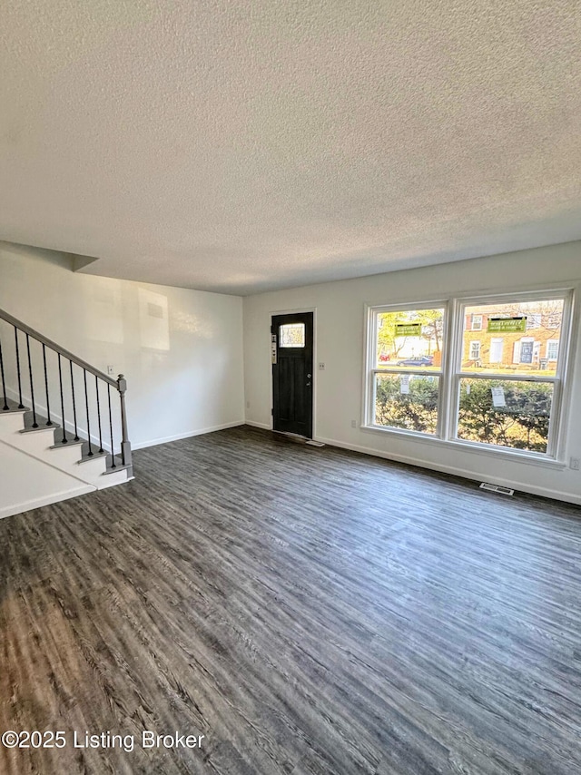 unfurnished living room with dark wood-type flooring and a textured ceiling