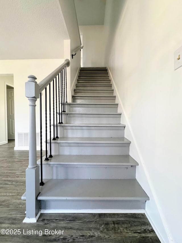 stairway featuring wood-type flooring and a textured ceiling