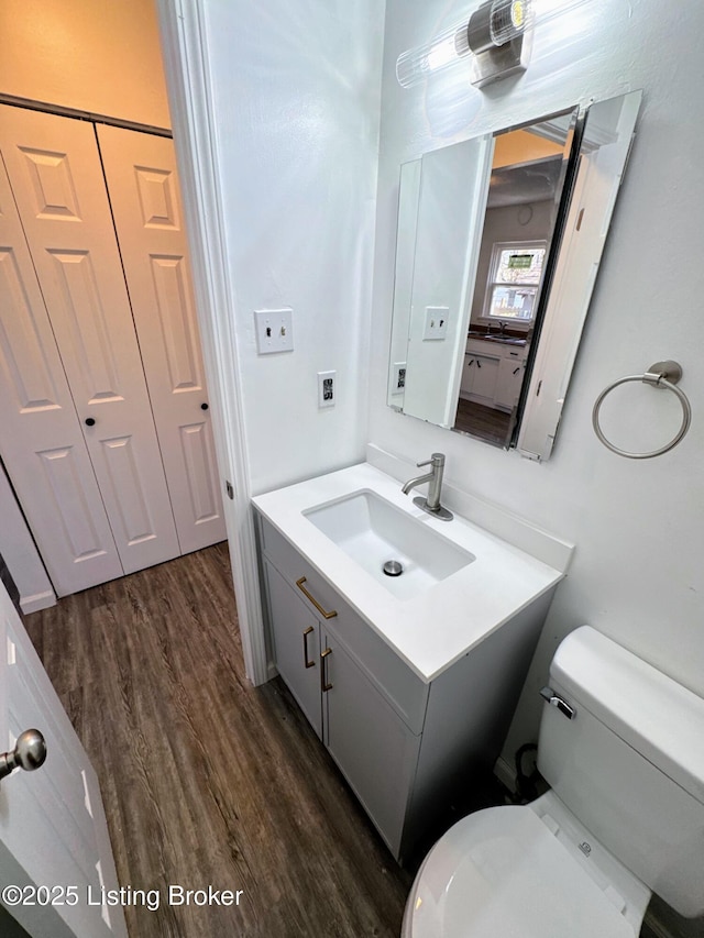 bathroom with toilet, vanity, and hardwood / wood-style floors