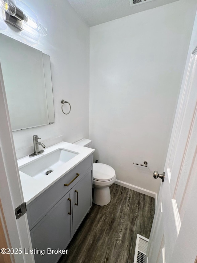 bathroom with hardwood / wood-style flooring, toilet, and vanity