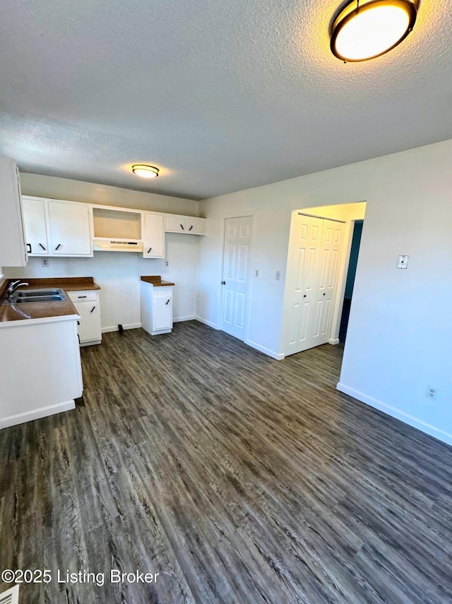 kitchen with dark wood-type flooring, sink, white cabinetry, and a textured ceiling