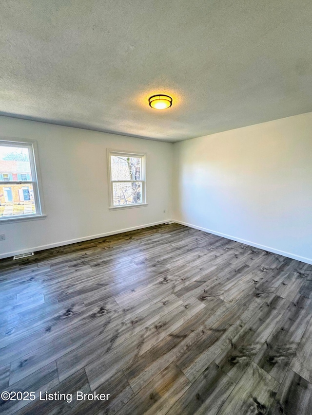 unfurnished room with a textured ceiling and dark hardwood / wood-style floors