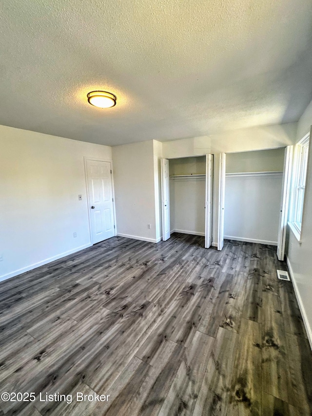 unfurnished bedroom with a textured ceiling and dark wood-type flooring