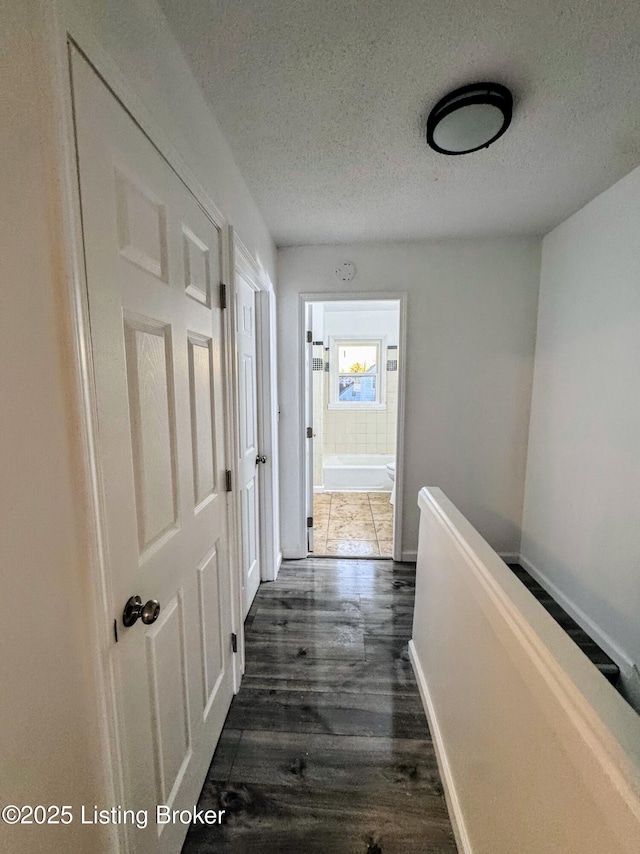 corridor featuring a textured ceiling and dark wood-type flooring