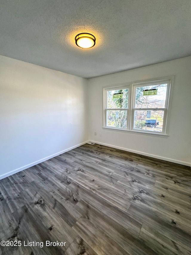 spare room with a textured ceiling and dark hardwood / wood-style floors