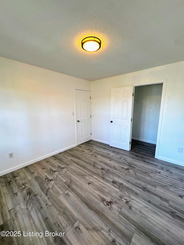 unfurnished bedroom featuring a textured ceiling, a closet, and dark hardwood / wood-style floors