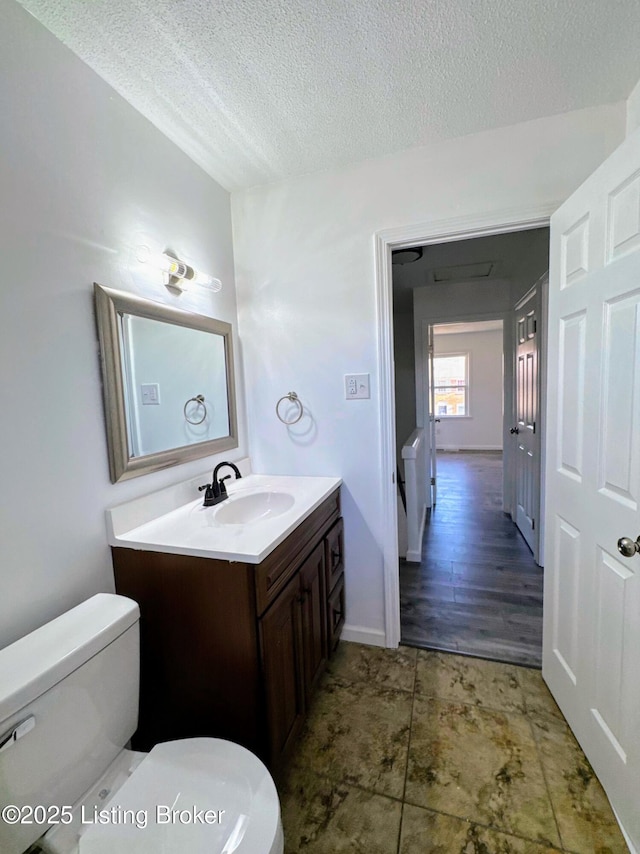 bathroom with a textured ceiling, toilet, and vanity