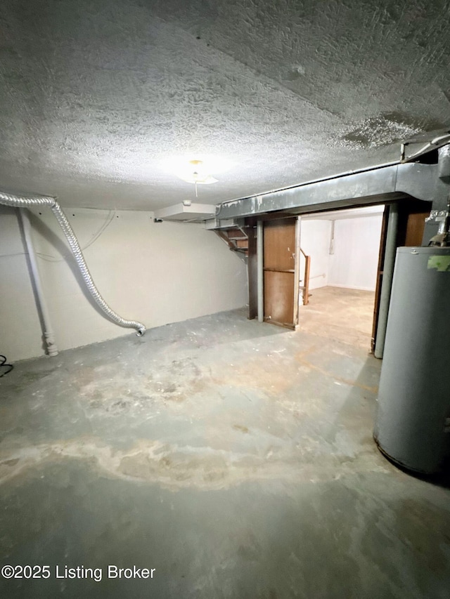 basement with a textured ceiling and water heater