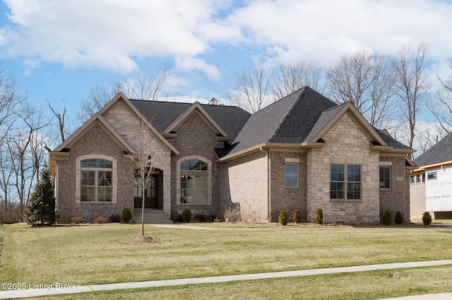 view of front of house with roof with shingles, brick siding, and a front lawn