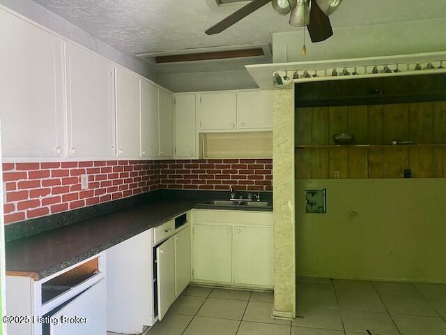 kitchen with a textured ceiling, white cabinetry, sink, light tile patterned flooring, and ceiling fan