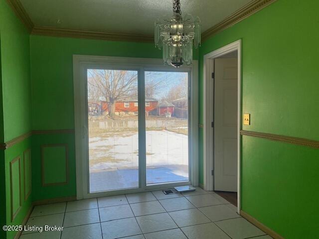 doorway with light tile patterned flooring, ornamental molding, and a notable chandelier