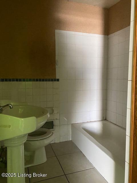 bathroom featuring toilet, a bathtub, tile walls, and tile patterned floors