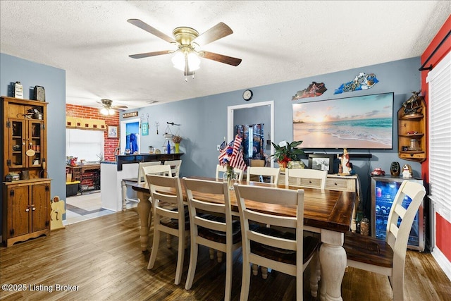 dining space featuring wood-type flooring, ceiling fan, and a textured ceiling