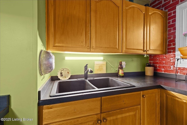 kitchen featuring sink and brick wall