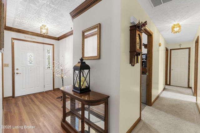 entryway featuring a textured ceiling, wood finished floors, visible vents, baseboards, and an inviting chandelier