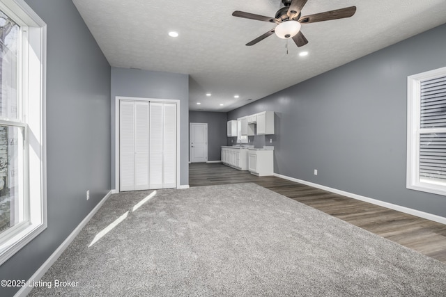 unfurnished living room featuring dark hardwood / wood-style flooring, ceiling fan, and a textured ceiling