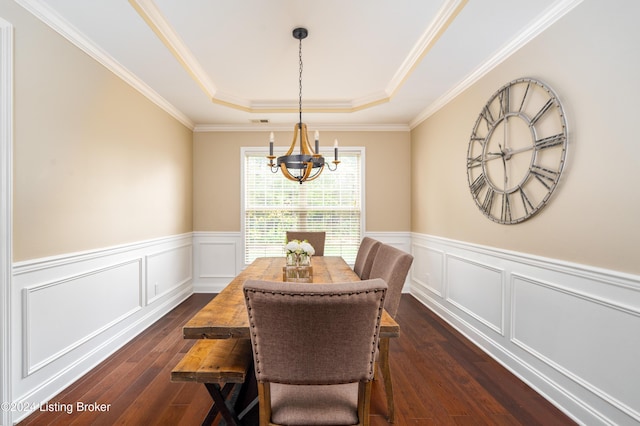 dining area with dark hardwood / wood-style floors, a raised ceiling, crown molding, and an inviting chandelier