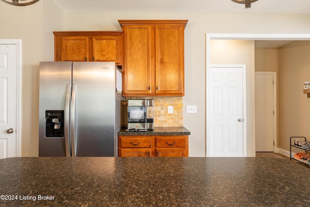 kitchen with decorative backsplash, stainless steel fridge, and dark stone counters