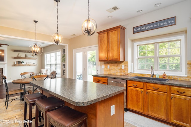 kitchen featuring a kitchen island, tasteful backsplash, sink, stainless steel dishwasher, and a breakfast bar area