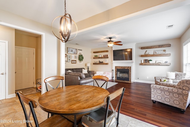 dining area with ceiling fan with notable chandelier and wood-type flooring