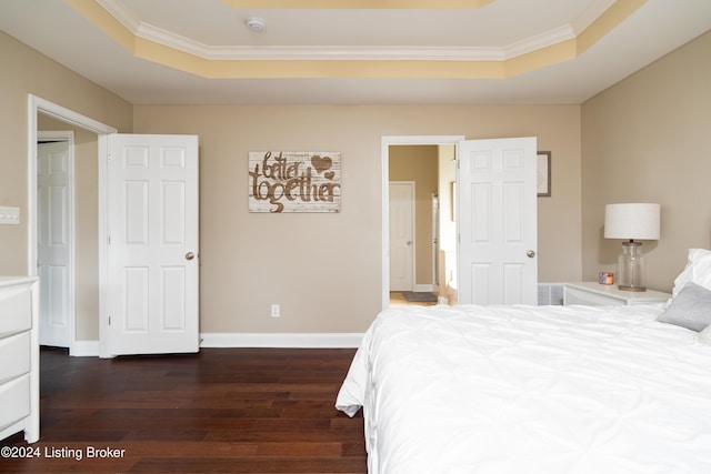 bedroom with crown molding, dark hardwood / wood-style floors, and a raised ceiling