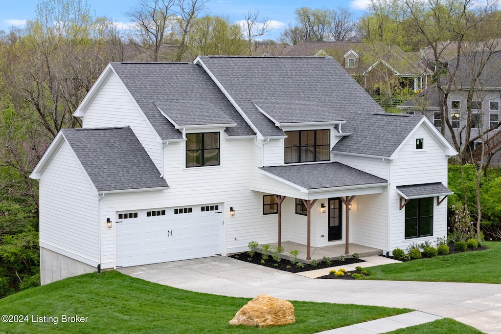 modern farmhouse style home with covered porch, a front yard, concrete driveway, and a shingled roof
