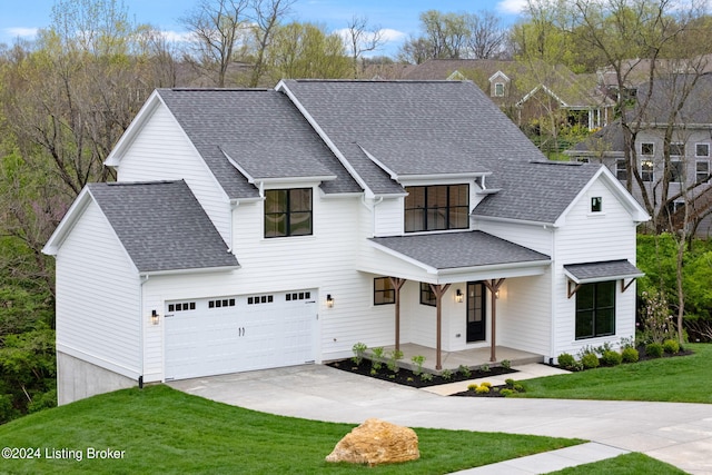 view of front of house featuring a front lawn, covered porch, and a garage