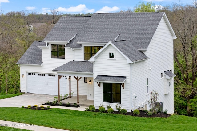 modern farmhouse featuring a garage, a front yard, and a porch